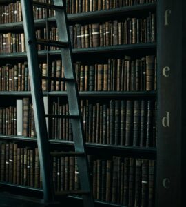 Mange bøker i bokhylle med en stige foran - illustrerer "Universitet som ikke vil tilrettelegge"